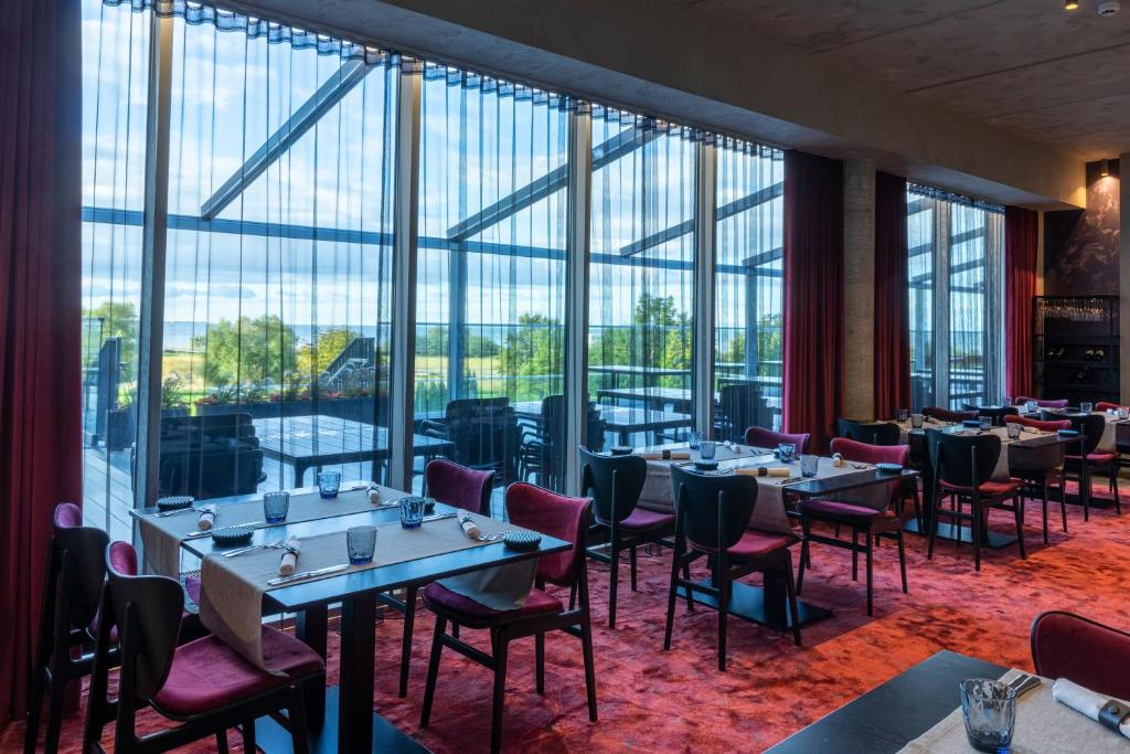 un ristorante con tavoli, sedie e ampie finestre di Spa Tervise Paradiis a Pärnu