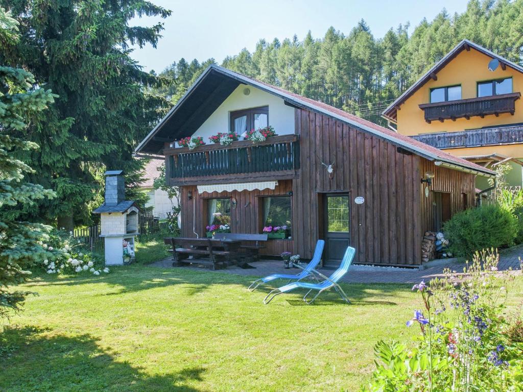a house with two chairs in the yard at holiday home with sauna Thuringian Forest in Neuhaus am Rennweg