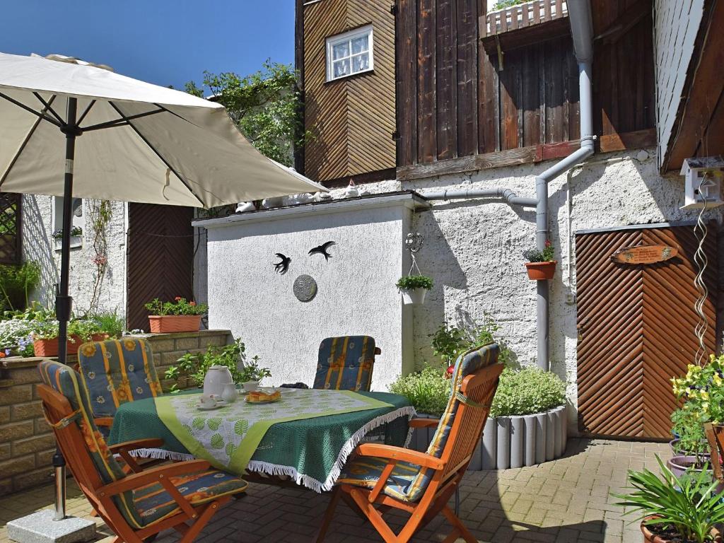 a table and chairs with an umbrella on a patio at Apartment in Thuringian Forest with garden in Oberweißbach