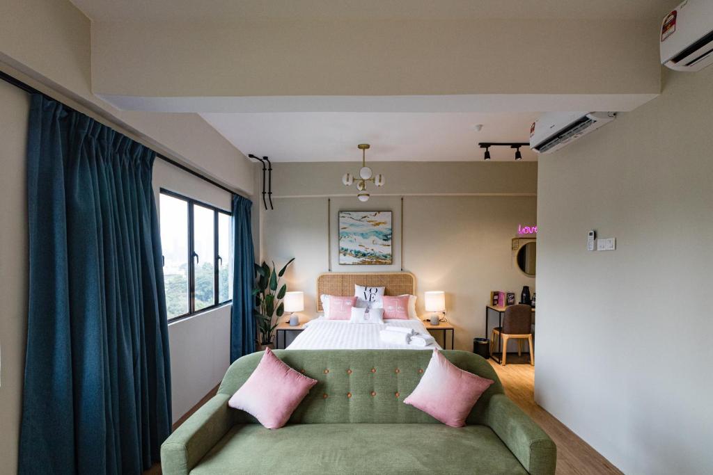 A bedroom with a green sofa at the foot of the bed opens onto a bright urban window view.