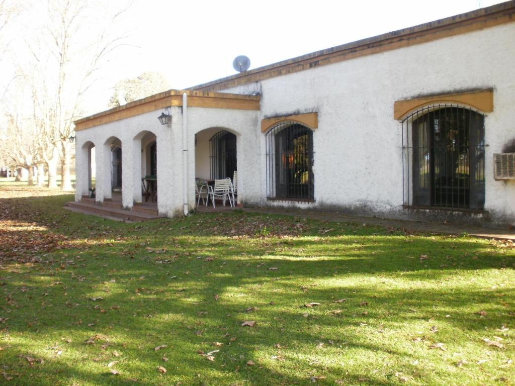 un antiguo edificio blanco con un patio de césped en Haras L'Etalon en Pergamino