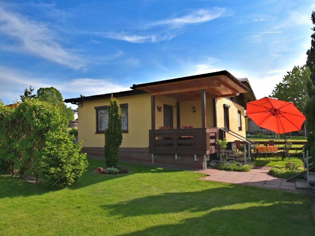 una pequeña casa con una sombrilla roja en el patio en Holiday home near the Schwarza Valley, en Grossbreitenbach