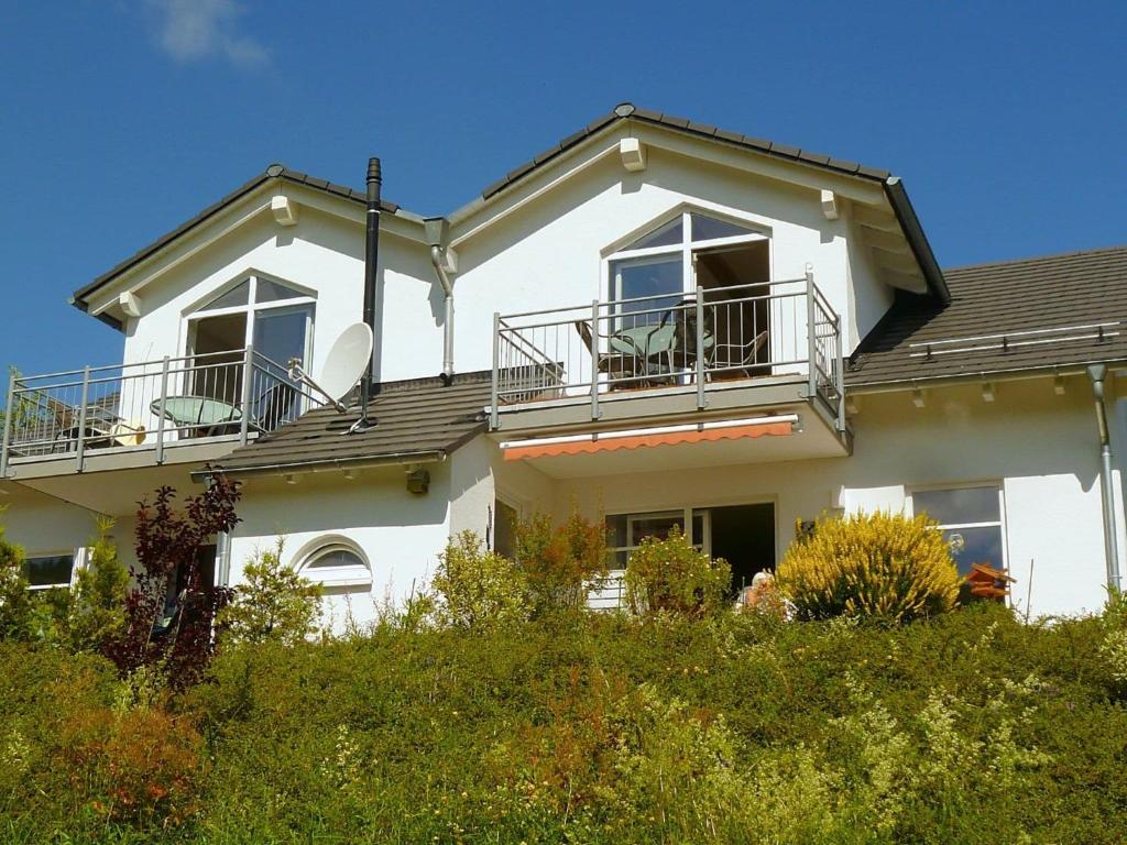 a white house with a balcony on top of it at Beautiful Apartment in Willingen with a Balcony in Willingen