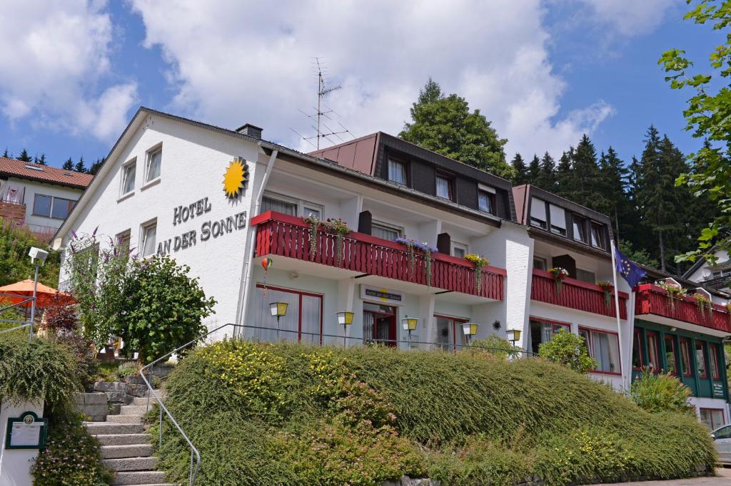 ein weißes Gebäude mit roten Balkonen darüber in der Unterkunft Hotel an der Sonne in Schönwald