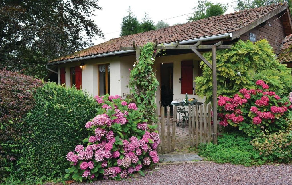 une petite maison avec des fleurs roses devant elle dans l'établissement Gites Des Blanchiries, à Aubin-Saint-Vaast