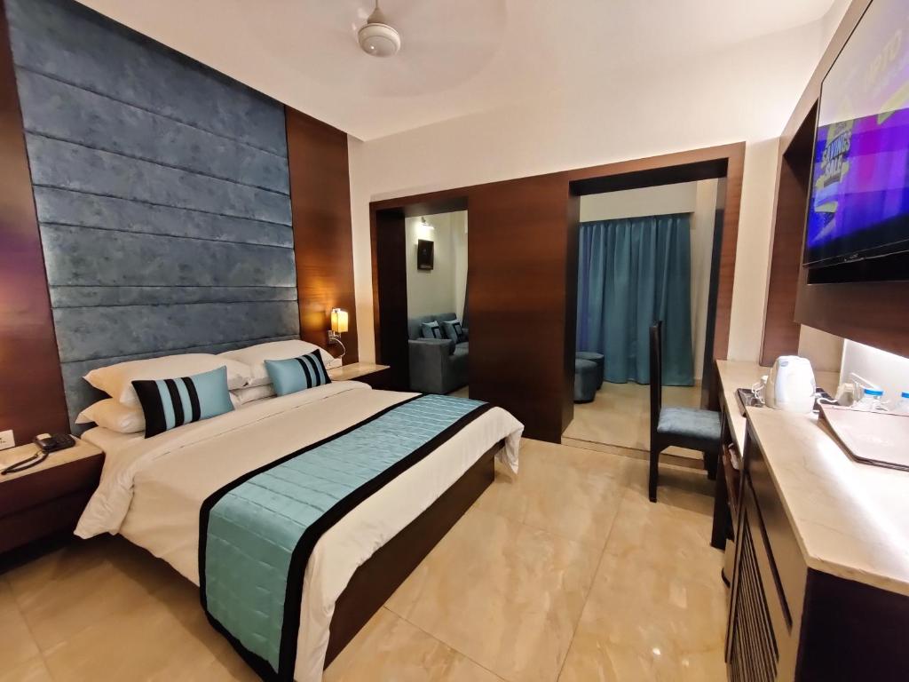 um quarto de hotel com uma cama grande e uma televisão de ecrã plano em The Samilton em Calcutá