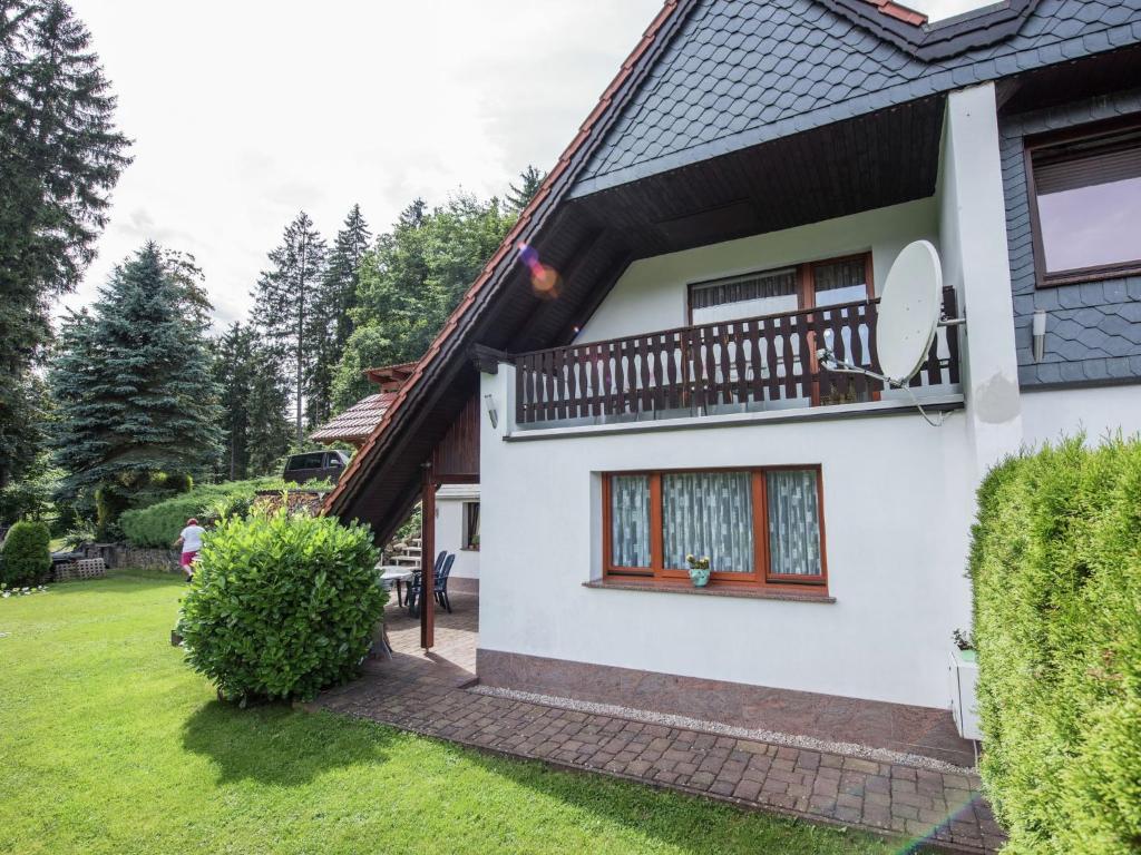 a white house with a balcony and a yard at Holiday home in Thuringia with terrace in Friedrichroda
