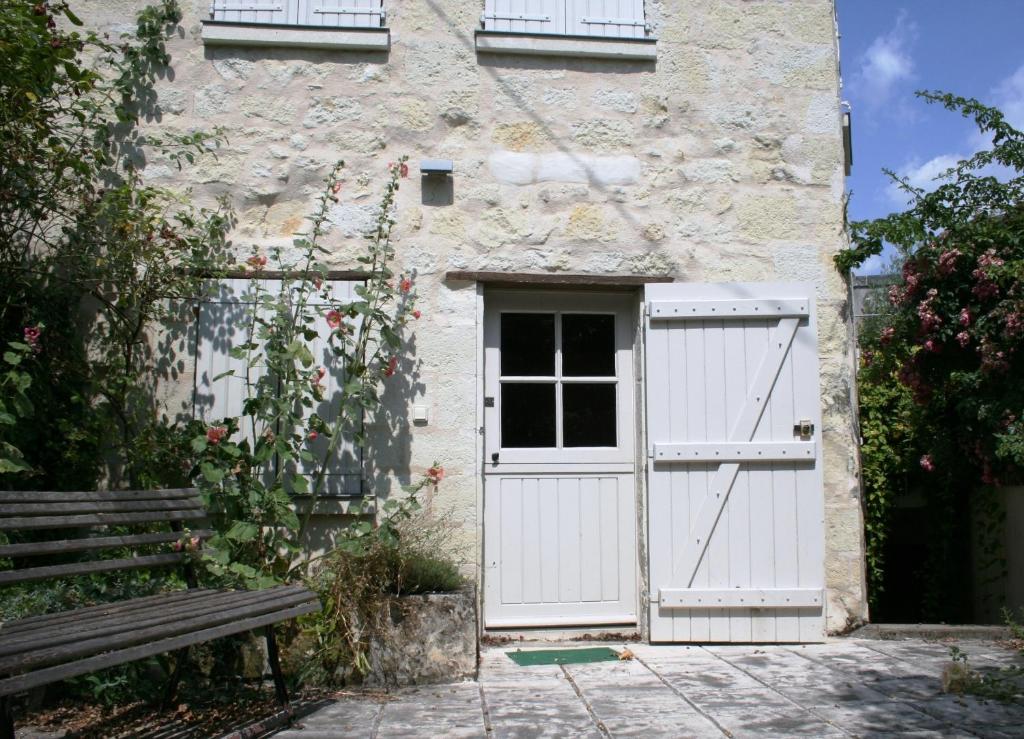 een witte deur op een stenen gebouw met een bank bij Gite Chateau de Chaintres in Dampierre-sur-Loire