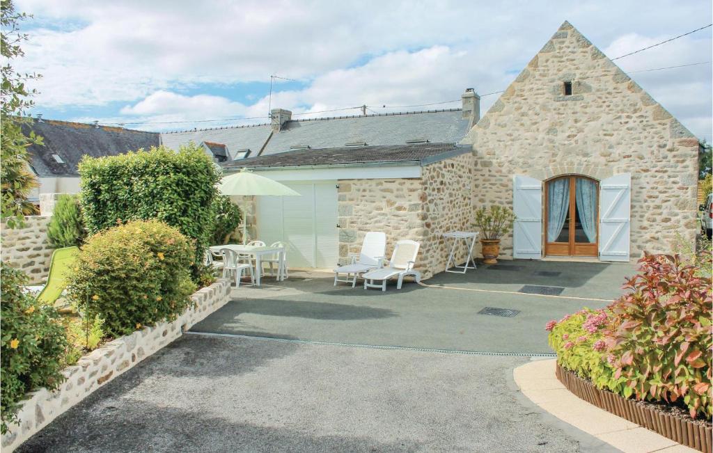 a stone building with a patio with chairs and an umbrella at Awesome Home In Lesconil With 2 Bedrooms in Plobannalec-Lesconil