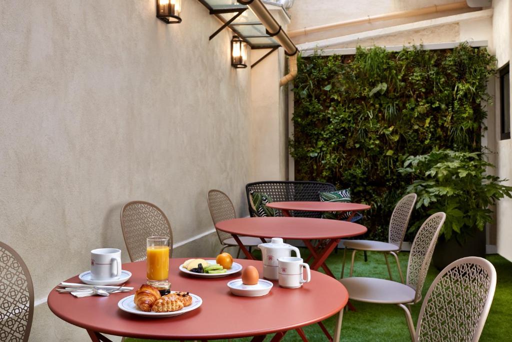 a patio with tables and chairs with food and drinks at Hôtel Harvey in Paris