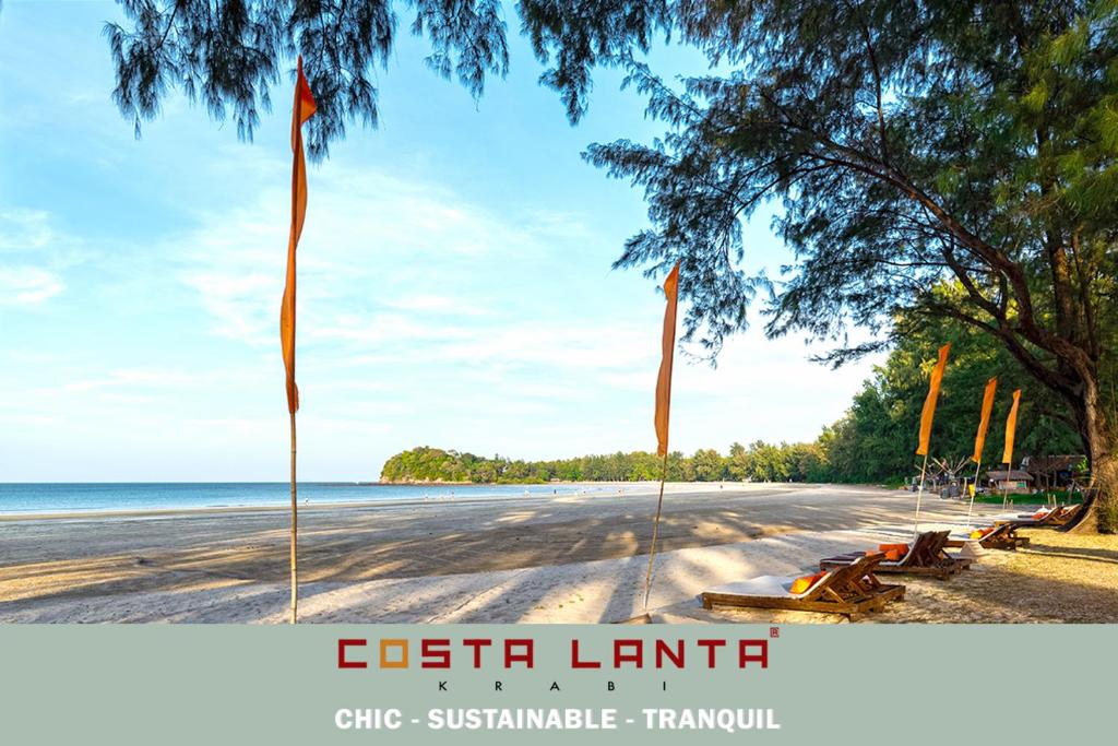 een uitzicht op het strand met twee vlaggen op de weg bij Costa Lanta - Adult Only in Koh Lanta