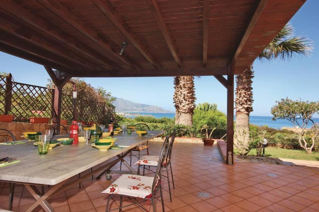 um pátio com uma mesa e cadeiras e o oceano em Villa Levante vista mare Cornino em Custonaci