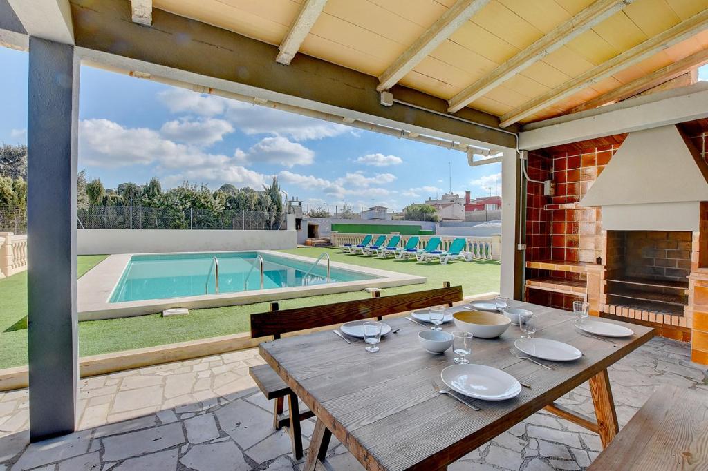 a patio with a wooden table and a swimming pool at Villa Maravillas 2 by Slow Villas in El Arenal