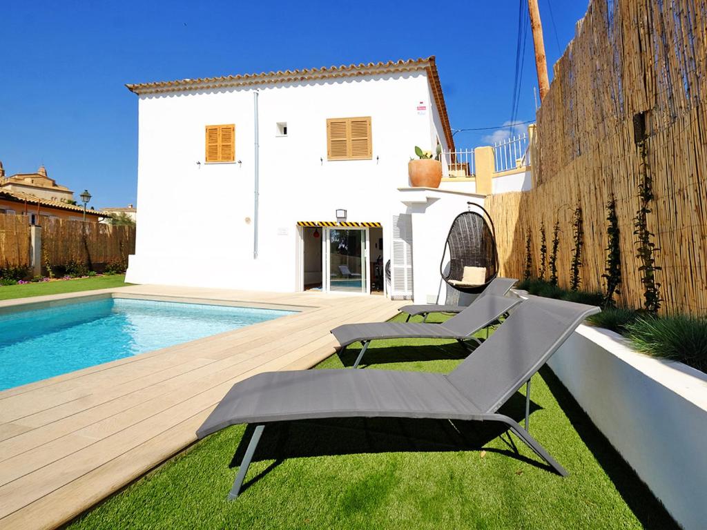 un patio trasero con piscina y 2 tumbonas en Villa Can Benet de sa Cubana by Slow Villas, en Calviá
