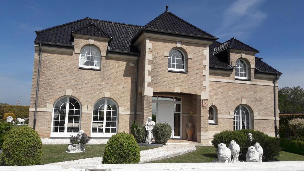 a brick house with statues in front of it at Maison d hôtes Salvatrice in Rouvroy