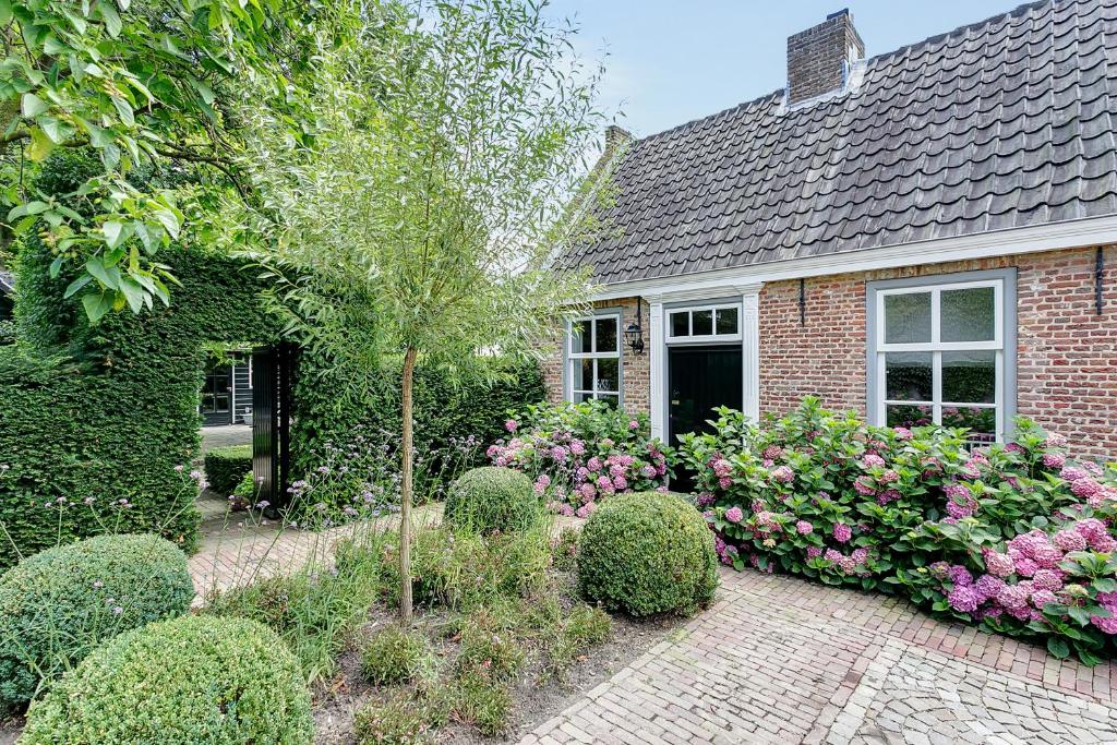 une maison en briques avec un jardin fleuri dans l'établissement B&B Van Gogh Cottage, à Nuenen