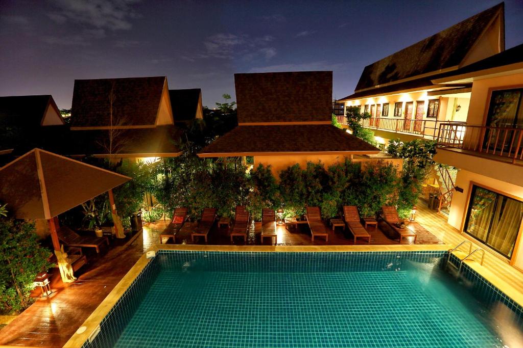 - une piscine en face d'un bâtiment la nuit dans l'établissement PloyKhumThong Boutique Resort, à Lat Krabang