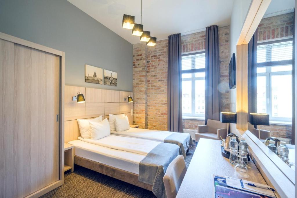 
a hotel room with two beds and a mirror at Wellton Centrum Hotel & SPA in Riga
