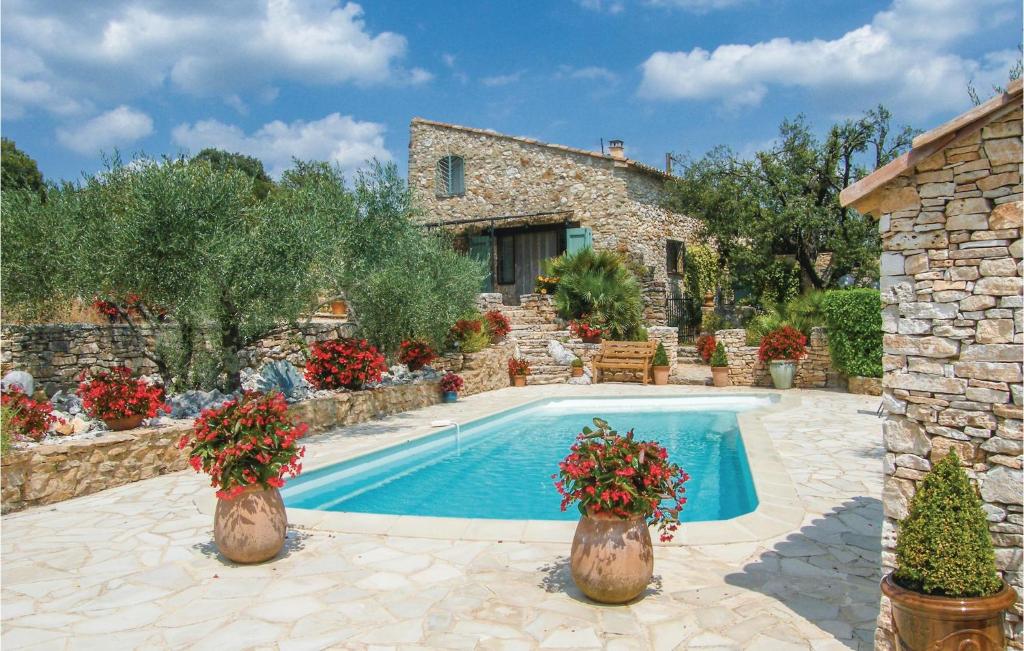 a swimming pool in front of a stone house with flowers at Gorgeous Home In Fontarches With Kitchen in Fontarèches