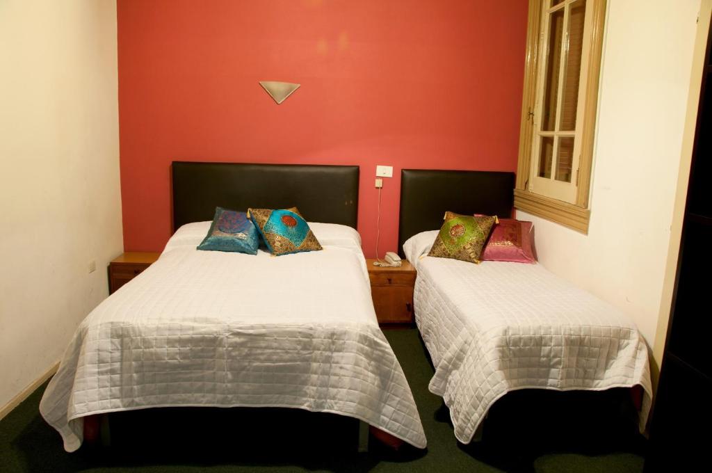two beds in a room with red walls at Hotel del Prado in Buenos Aires