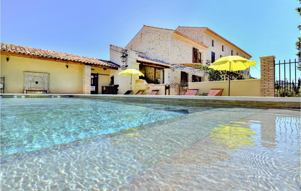 ein Pool vor einem Haus mit Sonnenschirmen in der Unterkunft 6 Bedroom Beautiful Home In Vallabregues in Vallabrègues