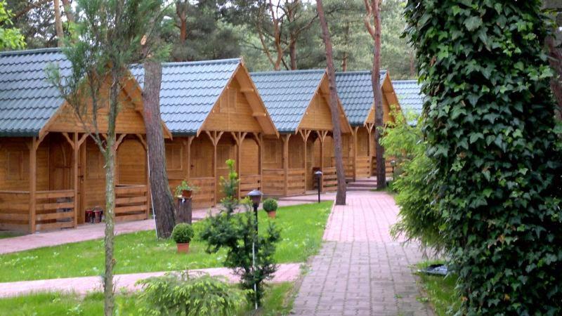 a large wooden cabin with a walkway in front of it at Jantar in Łazy