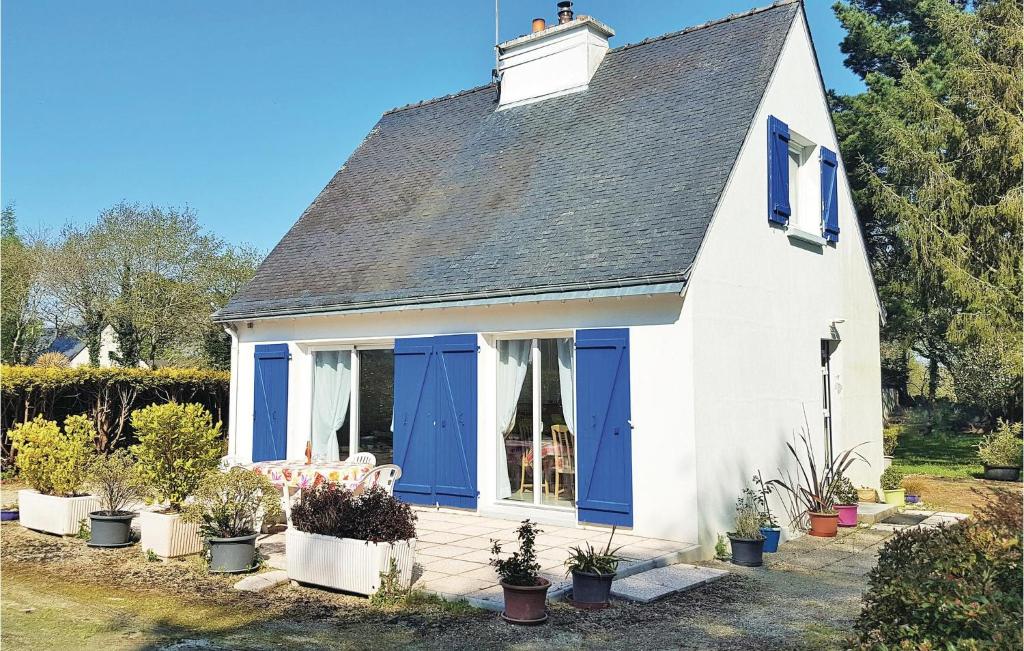 a white house with blue doors and potted plants at Nice Home In Riec Sur Belon With 3 Bedrooms in Riec-sur-Bélon