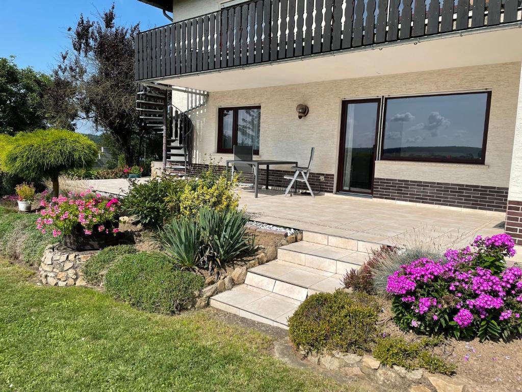 Cette maison dispose d'une terrasse avec une table et des fleurs. dans l'établissement Ferienwohnung in Frielendorf, à Frielendorf