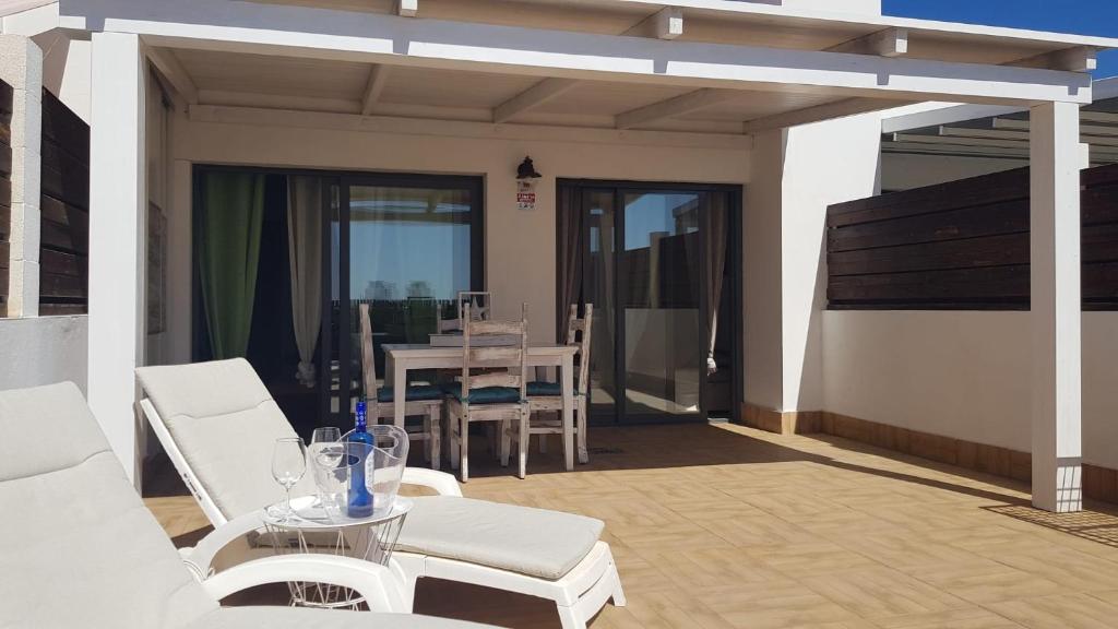 a patio with white chairs and a table and a dining room at ÁTICO BONITO Sea View in Puerto del Rosario