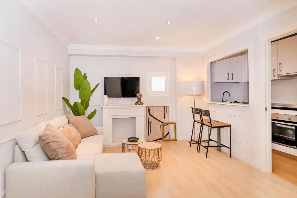 sala de estar con sofá blanco y cocina en BHost - The Special One, en Málaga