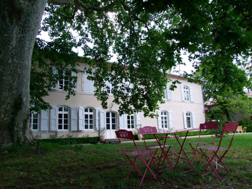 a white house with red chairs in front of it at Domaine de Lalande in Vénès