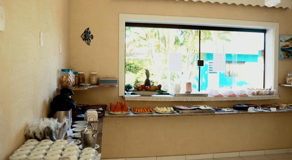 a kitchen with a counter with plates and a window at Pousada Porto do Itagua in Ubatuba