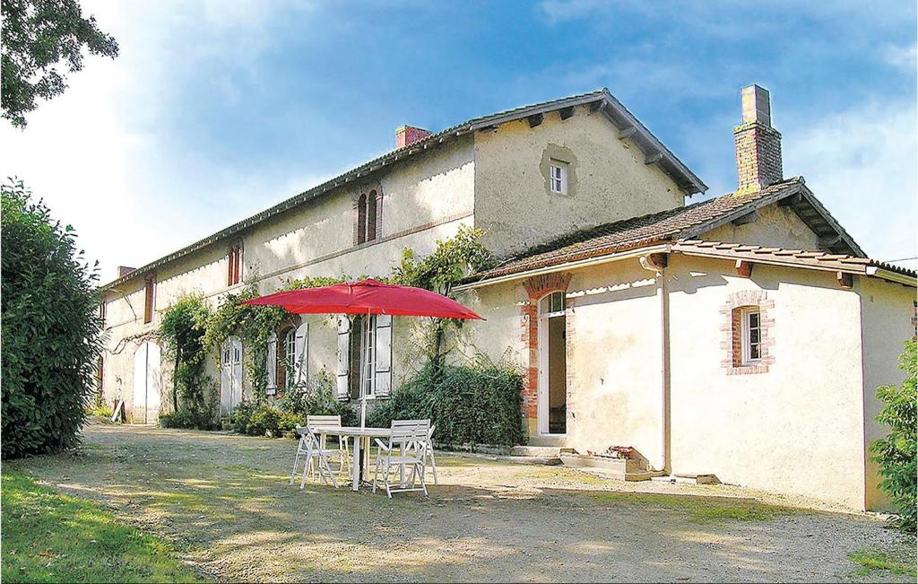 a table with a red umbrella in front of a building at Nice Home In La Chapelle Hermier in La Chapelle-Hermier