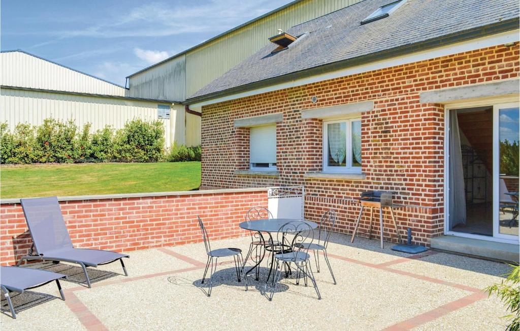 a patio with a table and chairs in front of a brick building at Les Renoncules Des Champs in Roisel