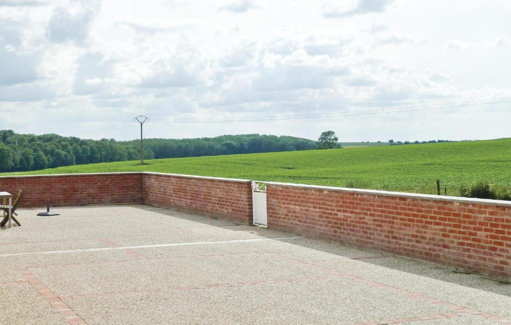 a brick wall with a field in the background at Les Renoncules Des Champs in Roisel