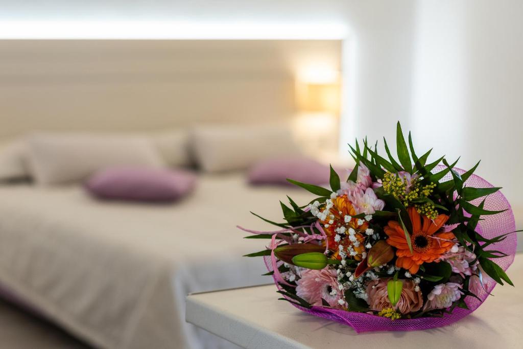 a bouquet of flowers on a table in a bedroom at Terinikos Hotel Junior Suites & Apartments in Ialyssos