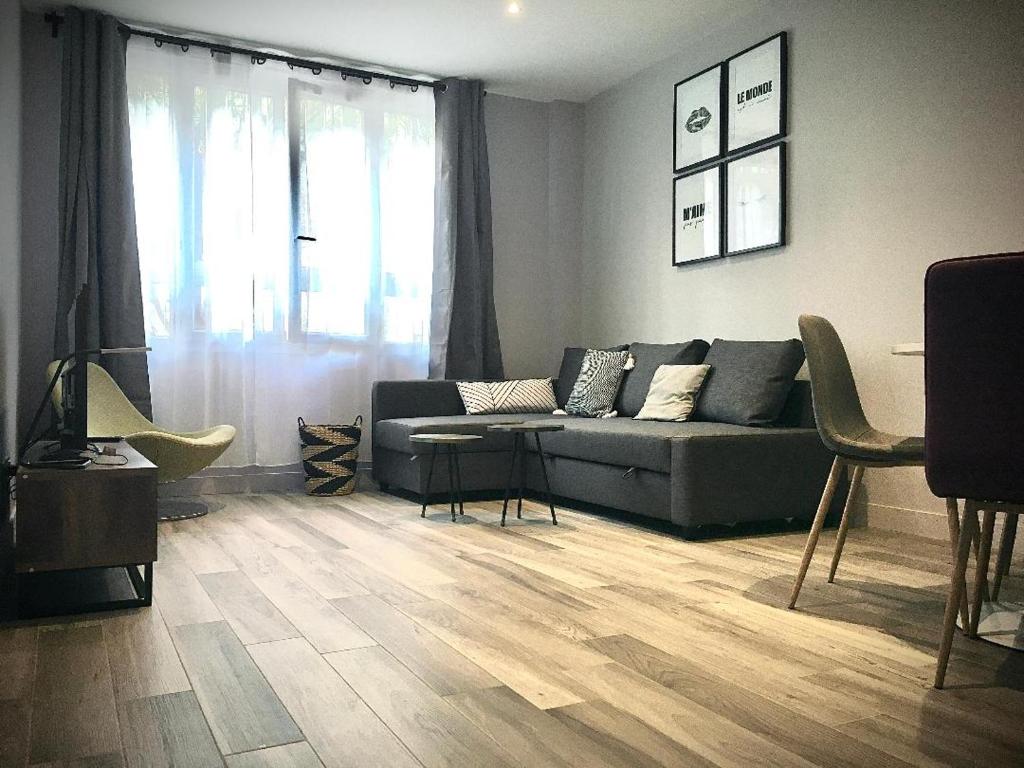 een woonkamer met een bank en een houten vloer bij 2 pieces proche metro, Montrouge in Montrouge