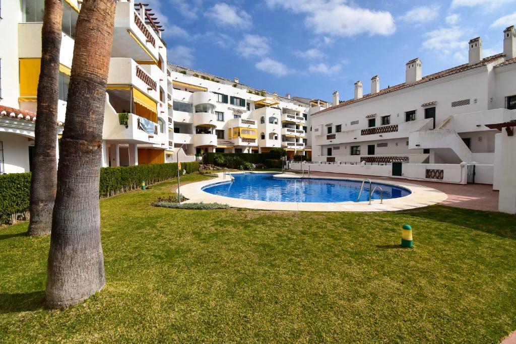 a swimming pool in a yard next to some buildings at Urb Pueblo del Parque, Luxury 2 bedroom apartment. Fantastic central location. in Benalmádena