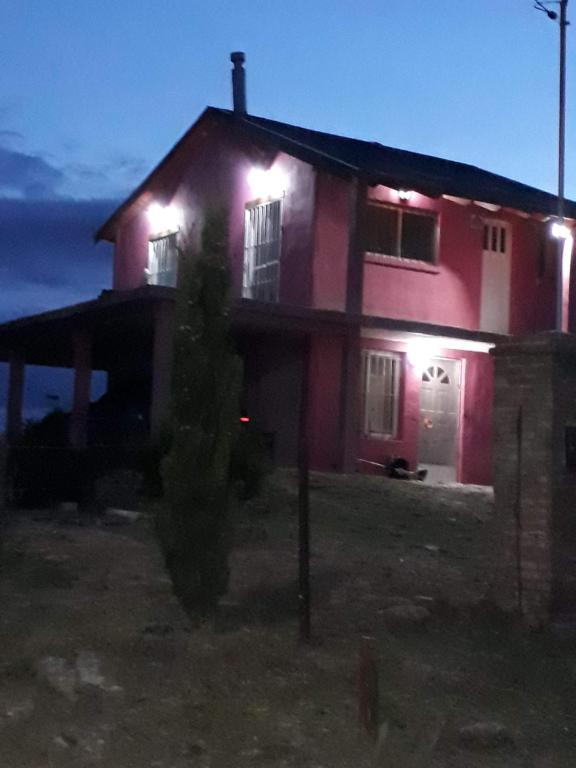 a red house with lights on it at night at La Rosadita - Casa de Montaña in Achiras