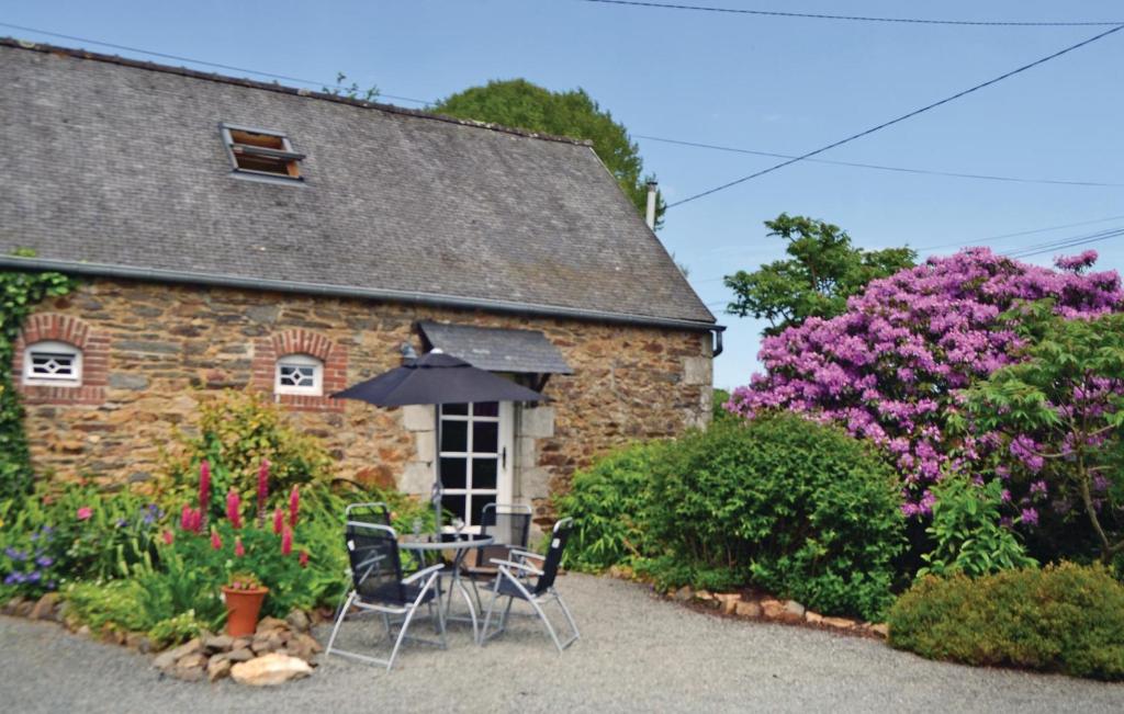 kamienny dom ze stołem, krzesłami i kwiatami w obiekcie Amazing Home In Callac De Bretagne With Kitchen w mieście Callac