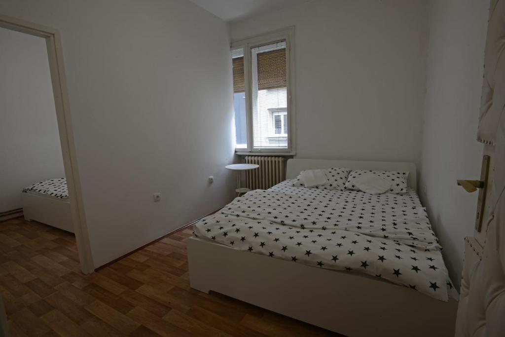 um pequeno quarto com uma cama e uma janela em Apartman Aleksandra centar em Belgrado