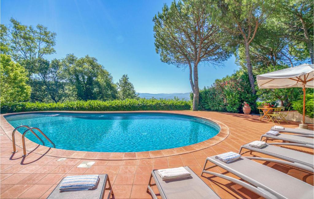 a swimming pool with chairs and an umbrella at Villa Caterina in Castiglion Fibocchi