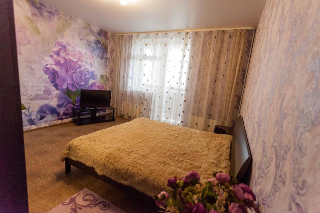 チュメニにあるApartment on Gazovikov 41のベッドルーム1室(ベッド1台付)、花の咲く窓が備わります。