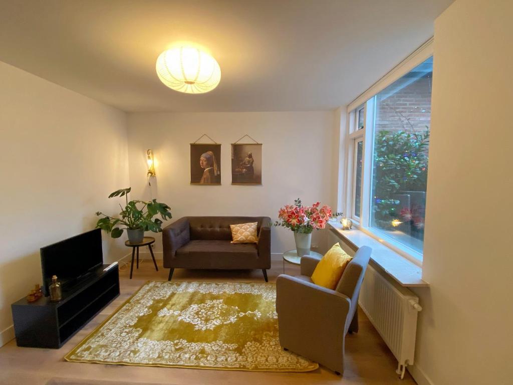 een woonkamer met een bank, een stoel en een raam bij Fijn guesthouse in Noordwijk
