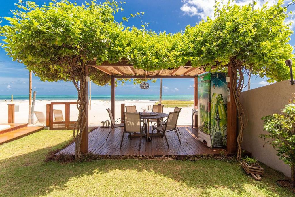 drewniany taras ze stołem i krzesłami na plaży w obiekcie Casa ao mar da Praia de Pirangi por Carpediem w mieście Parnamirim