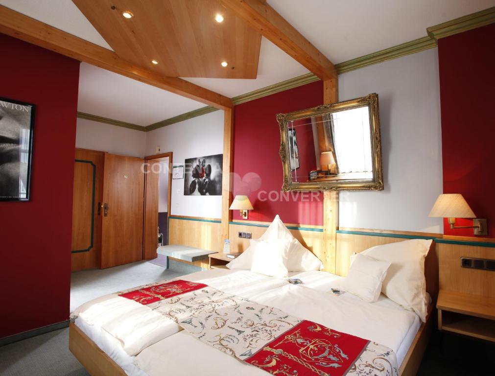 Schlafzimmer mit einem Bett und einem Wandspiegel in der Unterkunft Bebra's Hessischer Hof in Bebra
