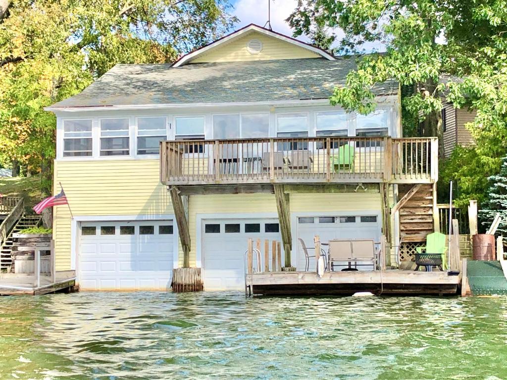 a house with a deck in the water at Lake Front Home Near Peek'n Peak in Findley Lake