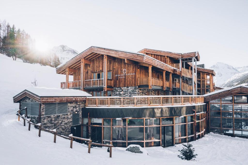 a large wooden building in the snow with snow at Les Balcons Platinium Val Cenis in Lanslevillard