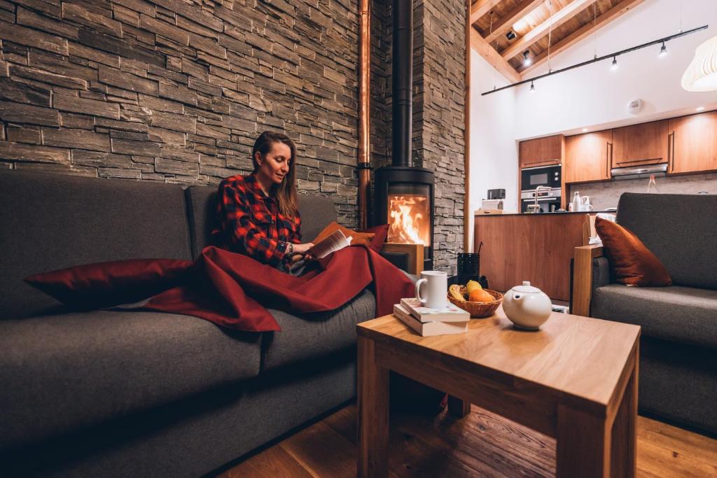 a man sitting on a couch reading a book at Les Balcons Platinium Val Cenis in Lanslevillard