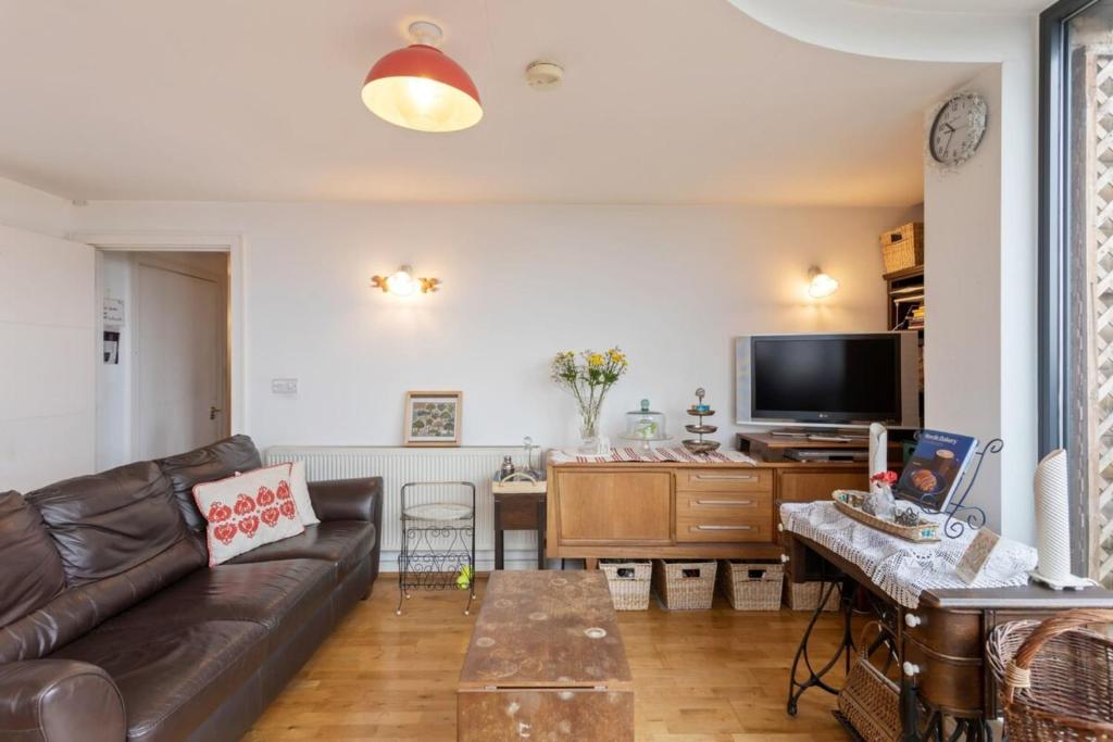a living room with a leather couch and a tv at Breathtaking 2 Bedroom Apartment with Balcony near Stoke Newington in London
